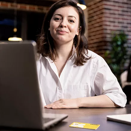 Foto mostra uma mulher trabalhando no escritório, com um Pluxee Gift na mesa