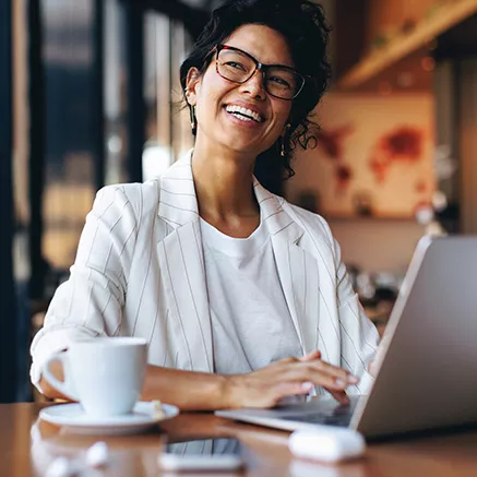 Foto de uma mulher sorrindo enquanto trabalha no escritório